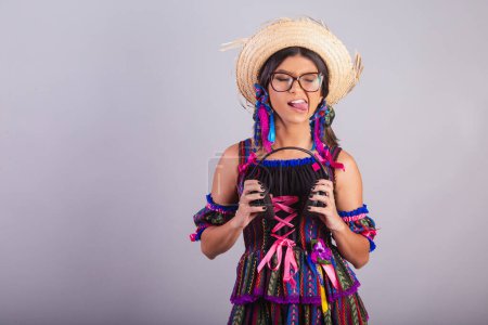 Téléchargez les photos : Femme brésilienne avec des vêtements de festa junina. tenant des écouteurs. - en image libre de droit