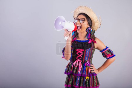 Téléchargez les photos : Femme brésilienne avec des vêtements de festa junina. tenant un mégaphone, annonçant des publicités. - en image libre de droit