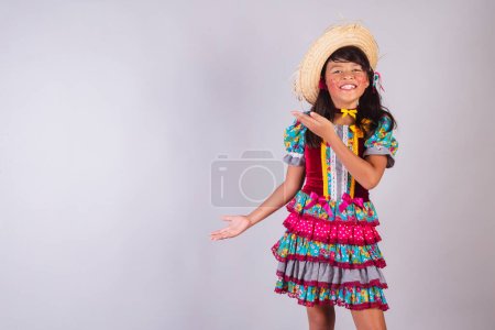 Téléchargez les photos : Enfant, fille brésilienne, avec des vêtements de fête de juin, présentant quelque chose sur le côté, produit, publicité. - en image libre de droit