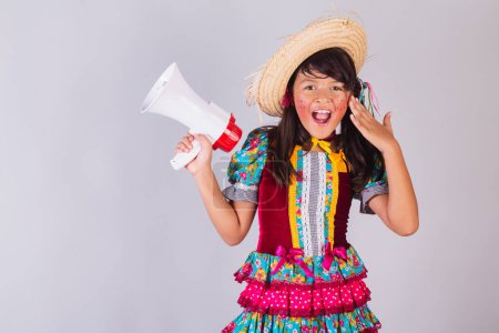 Téléchargez les photos : Enfant, fille brésilienne, dans les vêtements de la fête junina, tenant mégaphone, annonçant. - en image libre de droit