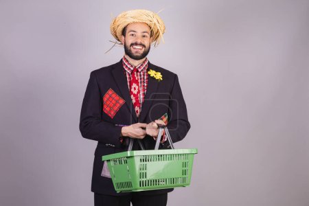 Photo for Brazilian man wearing typical clothes of festa junina, arraial, festa de so joo. with shopping basket - Royalty Free Image