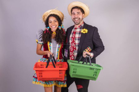 Photo for Brazilian couple, wearing June party clothes, fraternization in the name of So Joo, Arraial. with grocery basket, groceries - Royalty Free Image