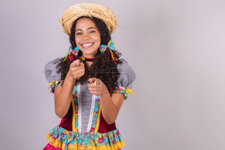 Black, Brazilian woman, wearing June party clothes, fraternization in the name of So Joo, Arraial. presenting product or advertisement on the side