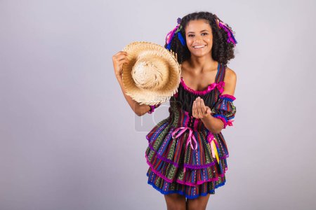 Photo for Black Brazilian woman wearing festa junina clothes. Fellowship of Saint John. Arraial, with straw hat. - Royalty Free Image