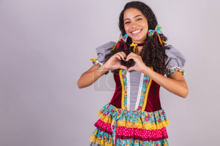 Black Brazilian woman wearing June party clothes, fraternization in the name of So Joo. Arraial heart, gratitude. 