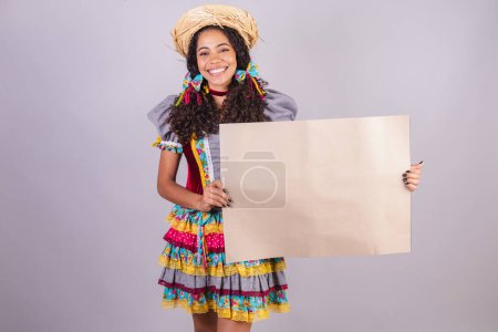Black, Brazilian woman, wearing June party clothes, fraternization in the name of So Joo, Arraial. Screaming holding panel for text or advertisement
