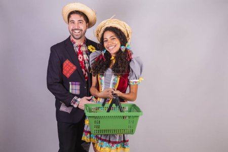 Téléchargez les photos : Couple brésilien, portant des vêtements de fête de juin, fraternisation au nom de So Joo, Arraial. avec panier d'épicerie, épicerie - en image libre de droit