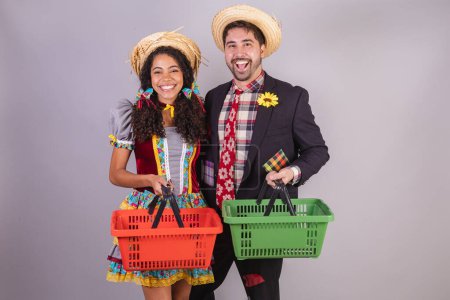Photo for Brazilian couple, wearing June party clothes, fraternization in the name of So Joo, Arraial. with grocery basket, groceries - Royalty Free Image