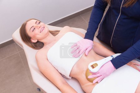 Photo for Esthetician, esthetician wearing lab coat, performing ultrasound procedure on female patient's abdomen. weight loss, slimming. - Royalty Free Image