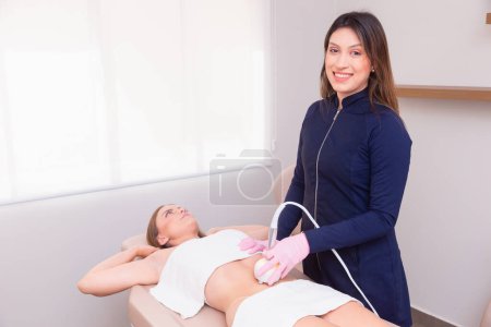 Photo for Esthetician, professional esthetician wearing lab coat, performing radio frequency procedure on the abdomen of a female patient. weight loss, slimming. - Royalty Free Image
