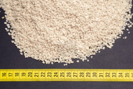 Photo for Wheat, heap of wheat flakes next to measuring tape, black background - Royalty Free Image