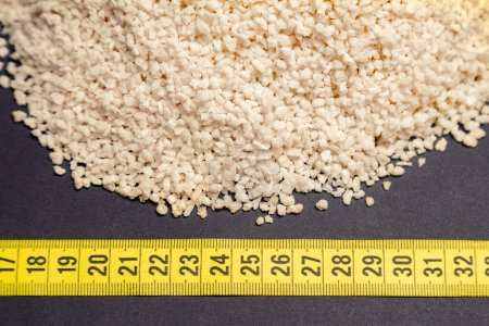 Photo for Wheat, heap of wheat bran next to measuring tape, black background - Royalty Free Image