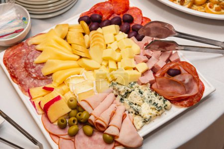Foto de Tabla de embutidos, con salamis, quesos y aceitunas, aperitivos y aperitivos para fiestas. - Imagen libre de derechos