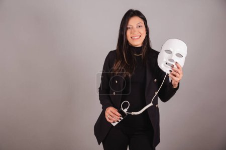 Photo for Business woman wearing black suit. Aesthetics professional. holding led mask. - Royalty Free Image