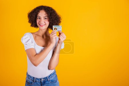 Photo for Caucasian model in white shirt and blue jeans holding driver's license. translation in English (motor vehicle driver's license) - Royalty Free Image