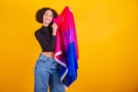 Téléchargez les photos : Modèle caucasien, en chemise noire et jean bleu, avec drapeau bisexuel, arc-en-ciel. - en image libre de droit