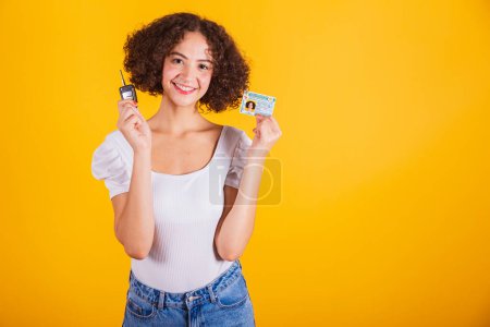 Photo for Caucasian model in white shirt and blue jeans holding driver's license and car keys. translation in English (motor vehicle driver's license) - Royalty Free Image
