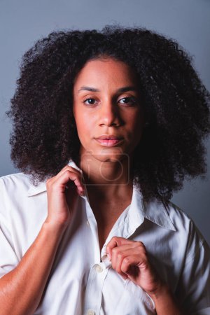 Foto de Medio cuerpo retrato, mujer brasileña negro, camisa blanca primer plano retrato, serio, mirando a la cámara. - Imagen libre de derechos