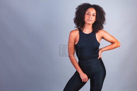 Foto de Retrato horizontal, medio cuerpo, mujer brasileña negra, camiseta negra, mano en la cintura. - Imagen libre de derechos