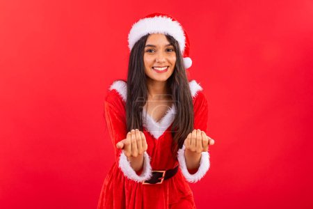 Photo for Brazilian woman, teenager, wearing Christmas clothes, smiling, inviting with both hands. - Royalty Free Image