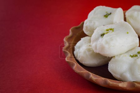 Photo for Bengali traditional sweet sandesh served on a clay plate for celebration of indian festivals. white jolbhora or talsaash sandesh, made of cottege cheese.close-up shot in red background. - Royalty Free Image