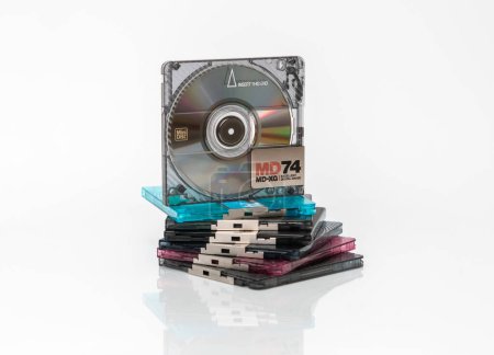 Photo for A minidisc stands vertically on a stack of other minidiscs on a white background with reflection - Royalty Free Image