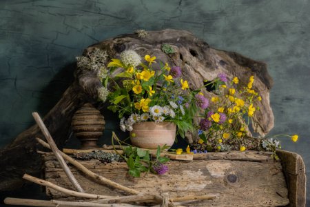 un ramo de flores silvestres en una olla de barro, en un estilo étnico