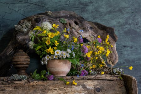 a bouquet of wild flowers in a clay pot, in an ethnic style
