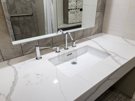 Téléchargez les photos : Lavabo moderne blanc propre avec miroir et douche en arrière-plan - en image libre de droit