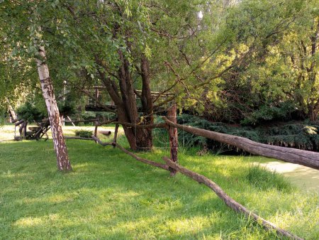 Foto de Una cerca de madera alrededor del pantano en el parque. Una cerca de madera hecha de ramas de árboles secos. - Imagen libre de derechos