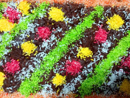 Foto de Textura superficial de un pastel rectangular decorado con crema de chocolate y virutas de coco multicolores. - Imagen libre de derechos