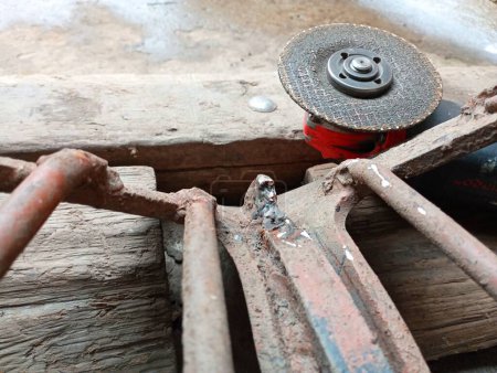 Foto de Una herramienta de disco de corte de metal eléctrico se encuentra cerca de equipos agrícolas para su reparación. - Imagen libre de derechos