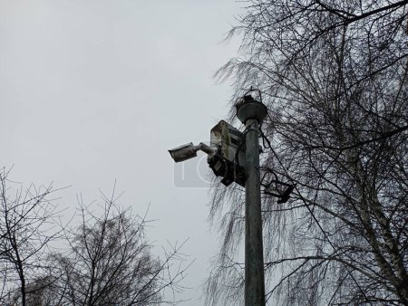 Photo for A pole with a built-in video surveillance camera and a security system control unit against a gray cloudy sky. Security system and video recording of the surrounding area. - Royalty Free Image