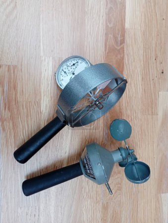 Two hand-held anemometers on the background of a wooden lacquered surface. Two devices for measuring wind speed and other gases.