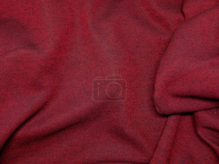 Texture of red fabric laid out with folds. Background of red fabric in a small cell.