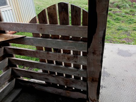 A wooden fence made of boards around a summer veranda with an open fence. an old wooden fence with a small rounded gate that opens.