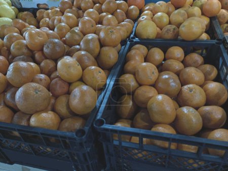Schachteln mit Mandarinen auf Lager. Viele Mandarinen werden in Plastikboxen gefaltet, um sie weiter auf dem Markt zu verkaufen. Textur reifer frischer Mandarinen. Das Thema Obst und Beeren.