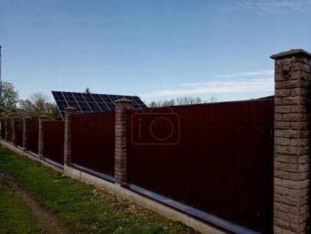 Hinter einem hohen Metallzaun befinden sich Sonnenkollektoren zur Stromerzeugung. Nutzung alternativer Energiequellen.