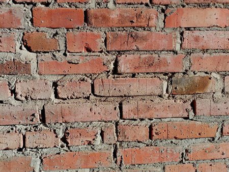 La texture d'un mur de briques en briques d'argile rouge disposées transversalement en rangées. Thèmes de construction et milieux de construction