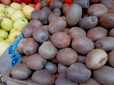Hermosos, deliciosos y maduros kiwis se venden en un mostrador en un pasillo al aire libre junto a deliciosas manzanas. El tema de las frutas y su venta en el mercado.