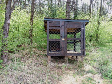 Dog enclosure in the forest made of wood and metal mesh is empty without a dog. A special building for keeping dogs.