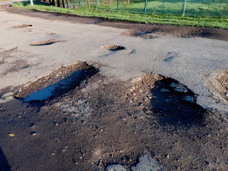 Big potholes on the asphalt road. The topic of bad road surface.
