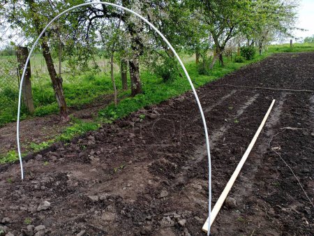 Le début de l'installation d'une serre faite de tuyaux de caisson et d'autres matériaux improvisés dans la cour près de la maison. Le thème est l'agriculture et la culture de légumes dans une serre.