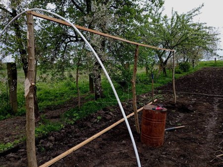 Ein Holzrahmen, der Rohre trägt, über die Polyethylenfolie gespannt wird, um mit den eigenen Händen aus vorhandenen Materialien ein Gewächshaus im eigenen Garten zu bauen. Rahmen eines Gewächshauses für Gemüseanbau