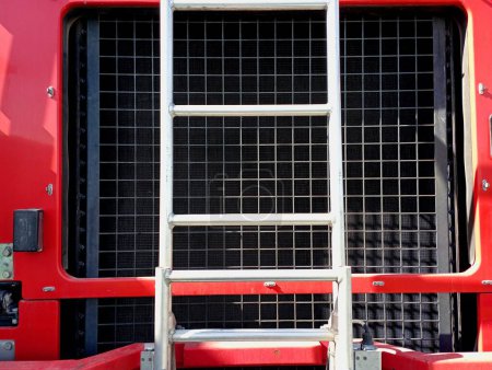 The engine cooling radiator of a special fire truck, in front of which a metal ladder is installed. Elements and parts of a fire truck.