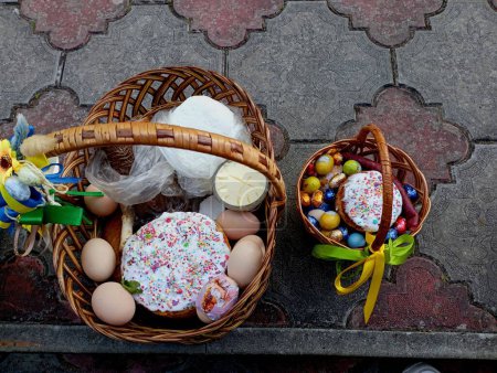 Two woven willow baskets filled with a variety of food for her consecration in the church are displayed on the cobblestones on the street. Consecration of food at Easter in the church.