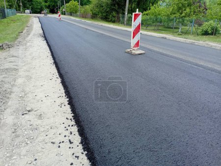 Signos especiales que dividen la calzada en dos carriles se encuentran en medio de la carretera de asfalto. Señales de tráfico durante la reparación de la superficie. Nuevo camino de asfalto.