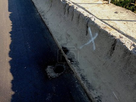 L'endroit marqué d'une marque blanche pour le drainage dans la couverture d'asphalte du pont. Drainage spécial pour l'écoulement des eaux de pluie.