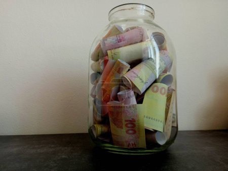 A three-liter glass jar is filled with money of various denominations. The topic of money and gifts.