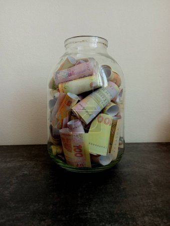 The glass jar is filled to the brim with bills. The topic of money storage. Money and banking.